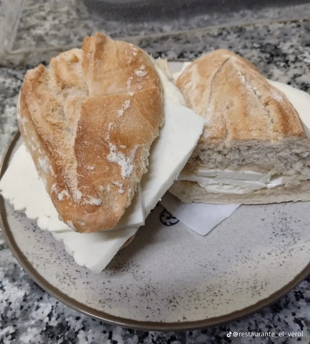 Bocadillo de queso partido por la mitad, servido en un plato del restaurante